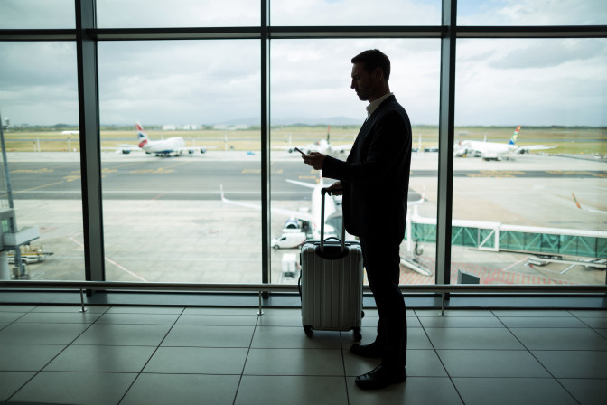 businessman-with-luggage-using-mobile-phone.jpg